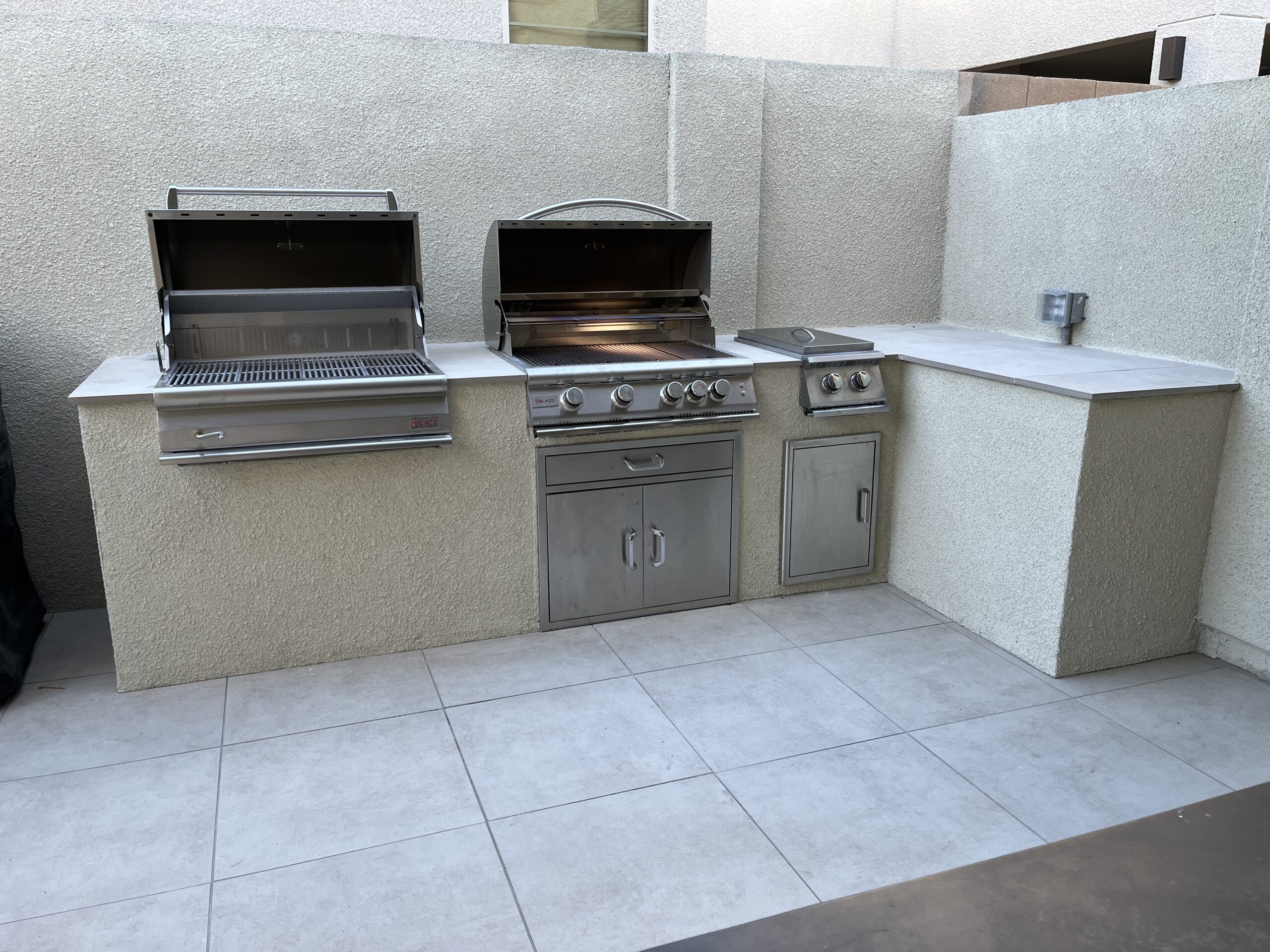 A large outdoor grill and sink in an outside kitchen.